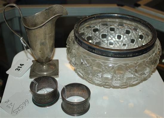 Silver helmet shaped cream jug, a circular cut glass bowl with silver rim and a pair of silver napkin rings